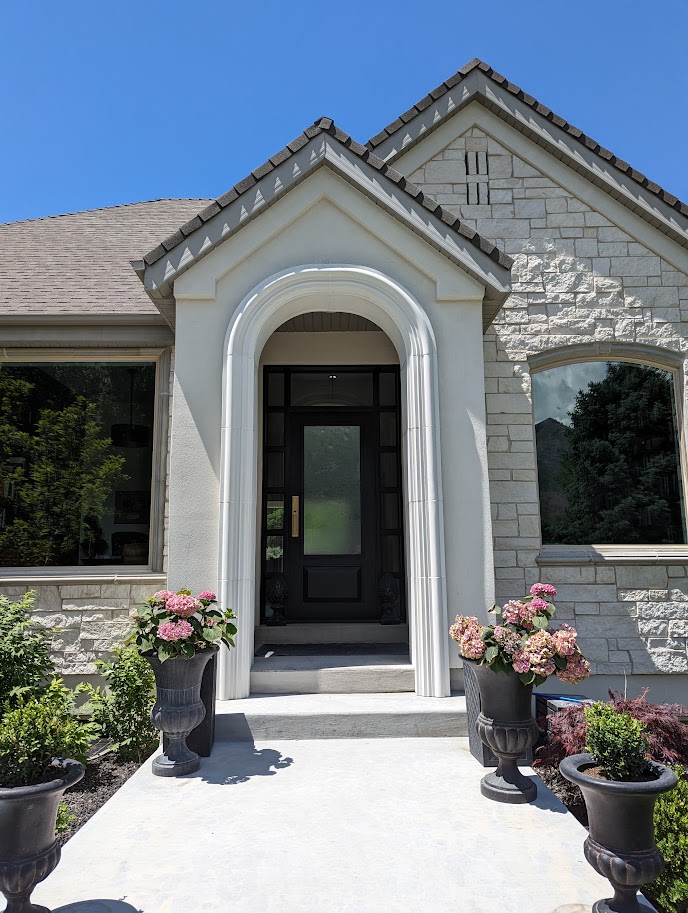 Cast limestone arched entry surround with columns on a stone home