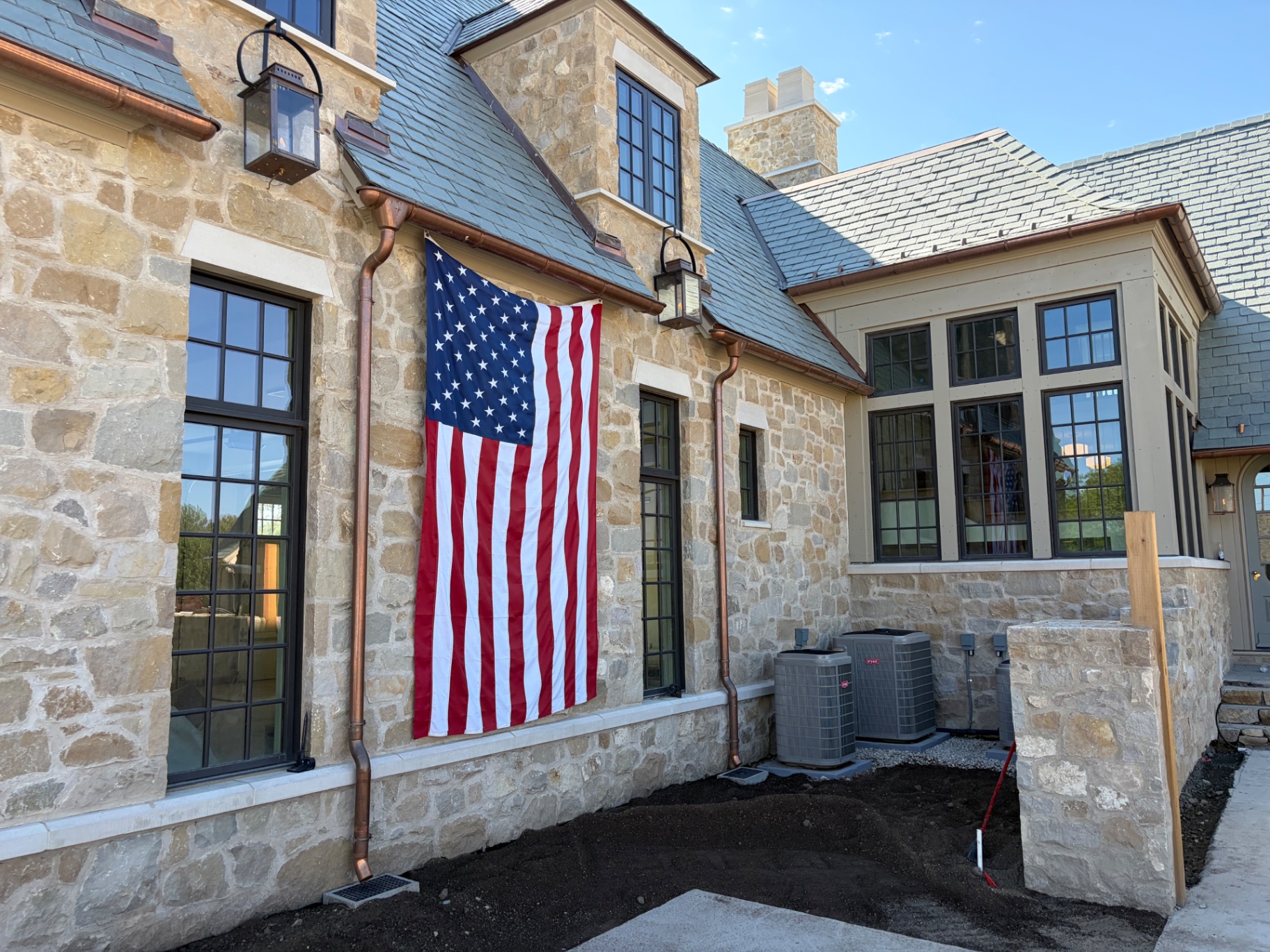 Close-up of hand-laid stone masonry wall with cast stone sills and copper downspouts