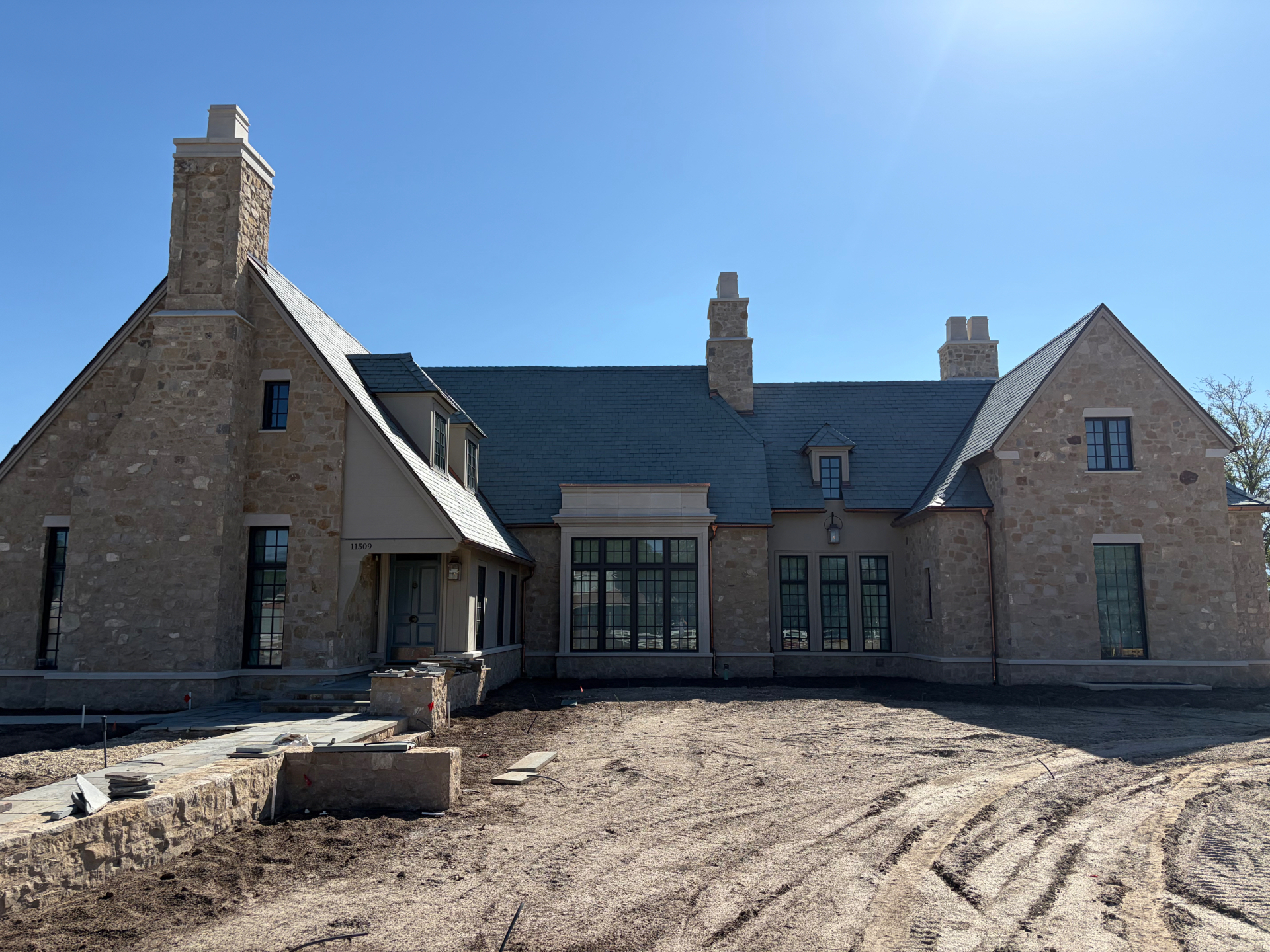 Stone masonry home elevation with matching stone chimneys and cast stone trim
