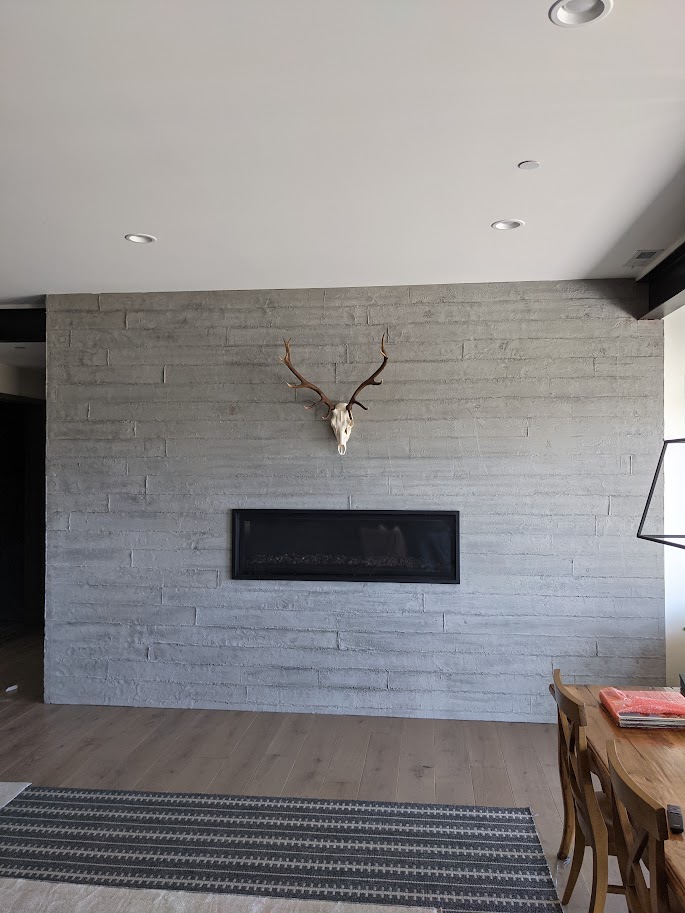 Board-formed gray plaster fireplace wall with linear firebox