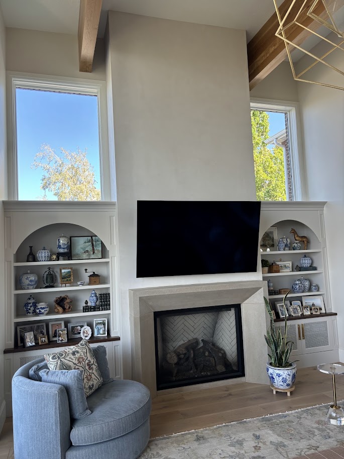 Cast limestone fireplace mantel between arched built-in bookcases