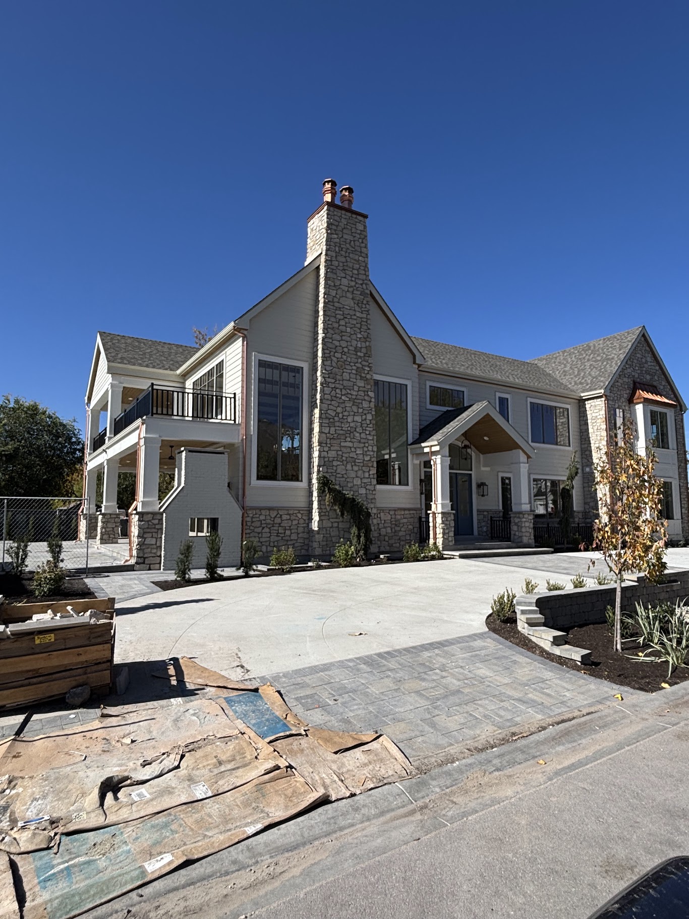 New stone masonry home with tall stone chimney, stucco gables, and cast stone trim