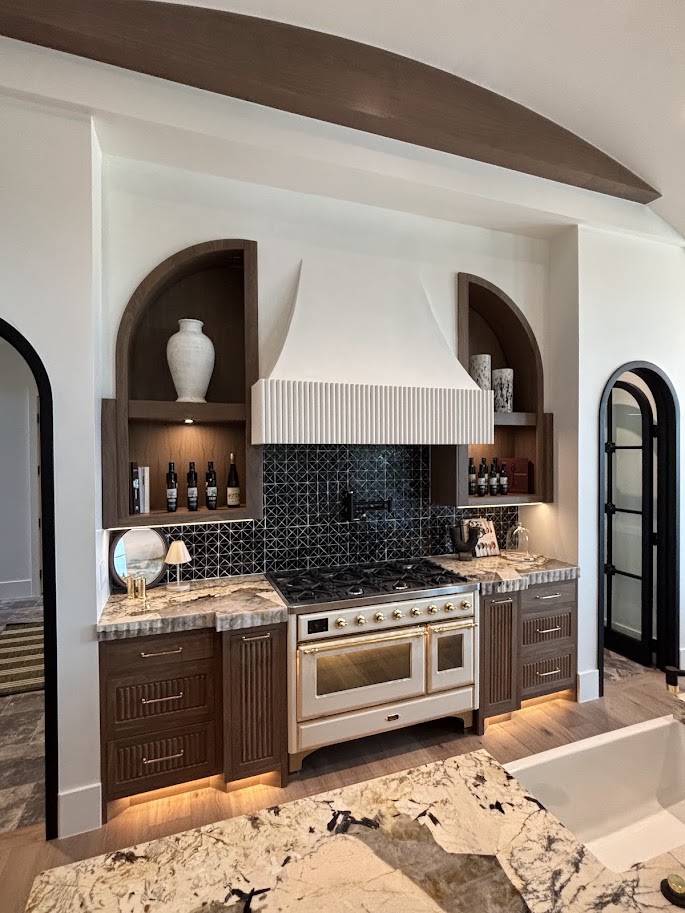 Fluted cast limestone range hood with arched niches in a custom kitchen