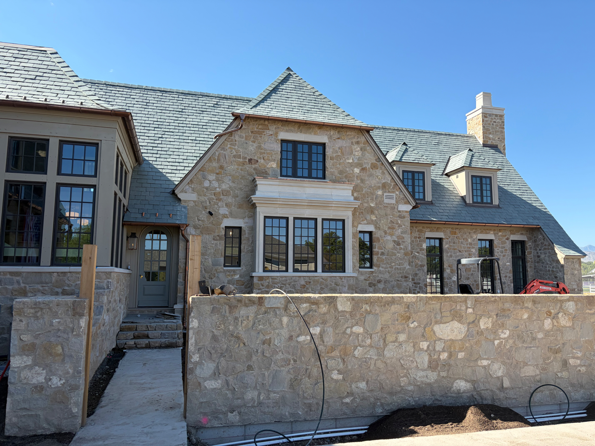 Tumbled stone home exterior with cast stone window surround and stone garden wall