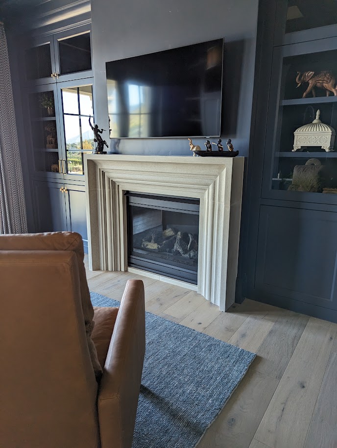 Stepped cast limestone fireplace surround in a navy built-in living room