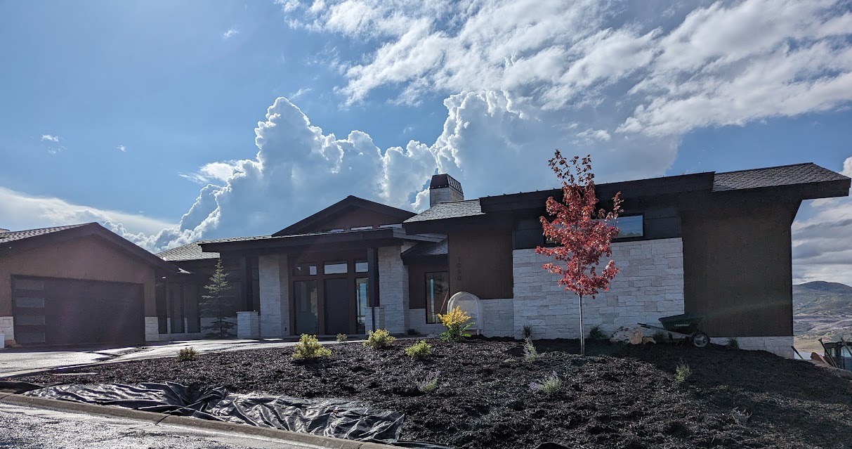 Mountain home with dark stucco siding and white stone veneer