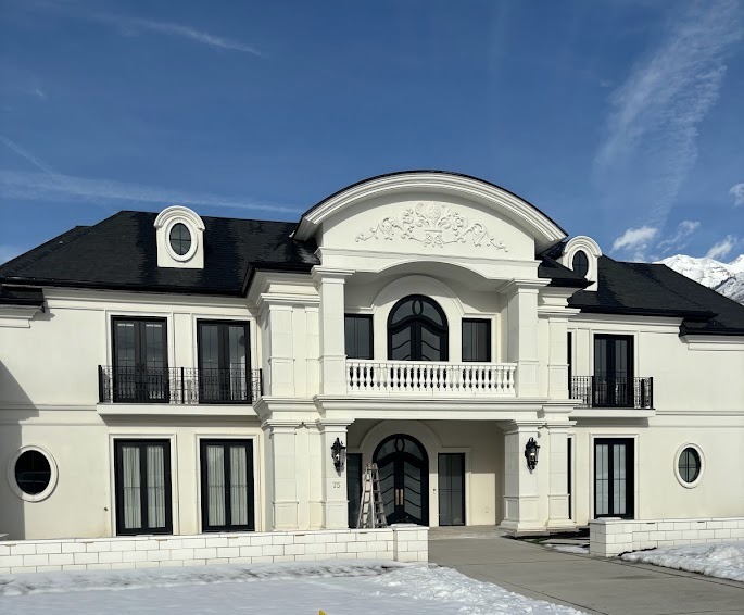 Ornate white stucco estate exterior with cast stone columns and detailed pediment in Utah