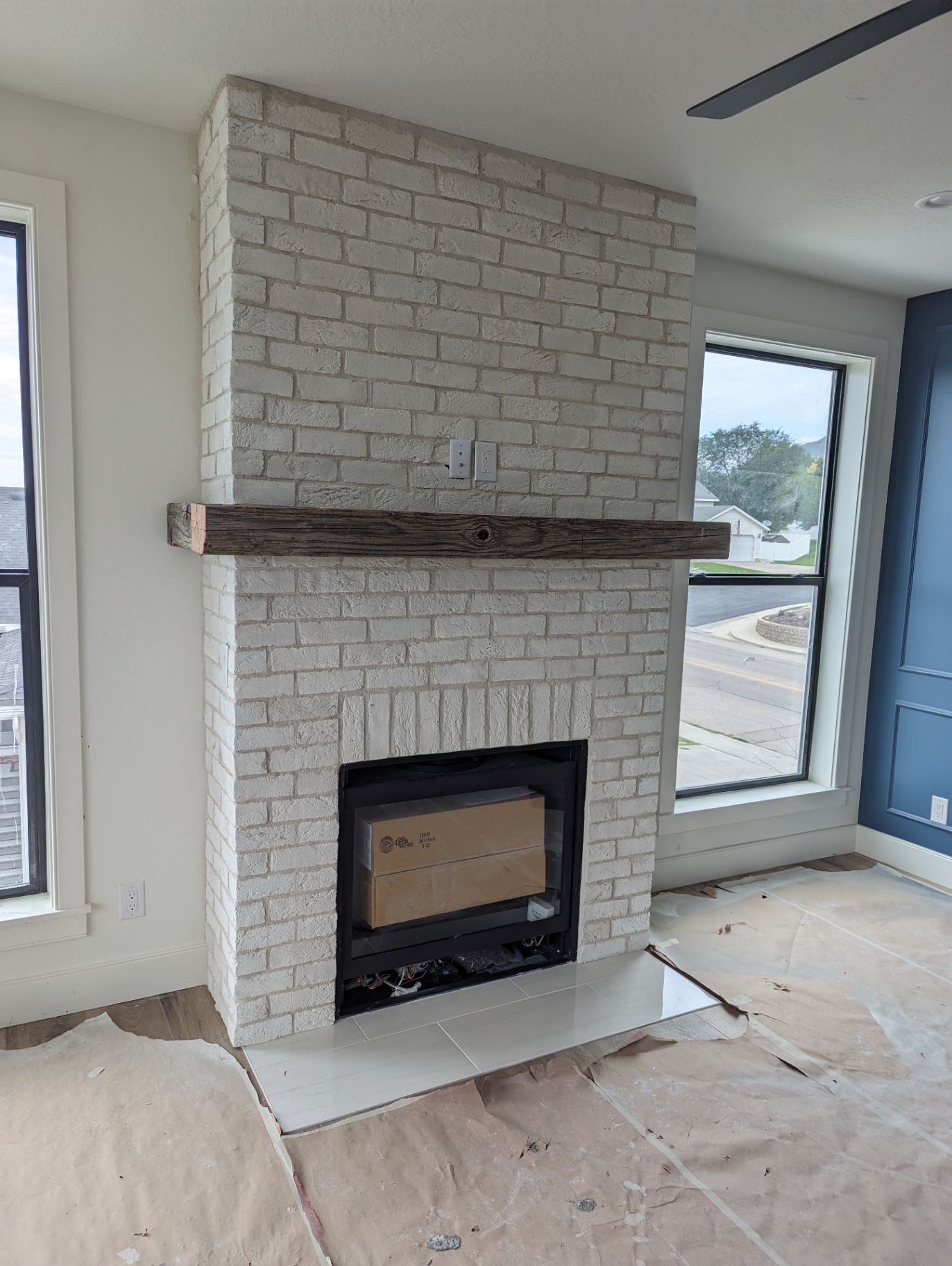 Whitewashed brick fireplace with plaster finish and reclaimed beam mantel