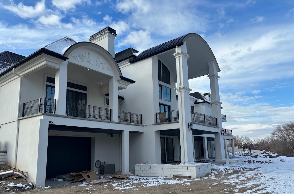 Rear elevation of a white stucco home with arched balconies and column detailing